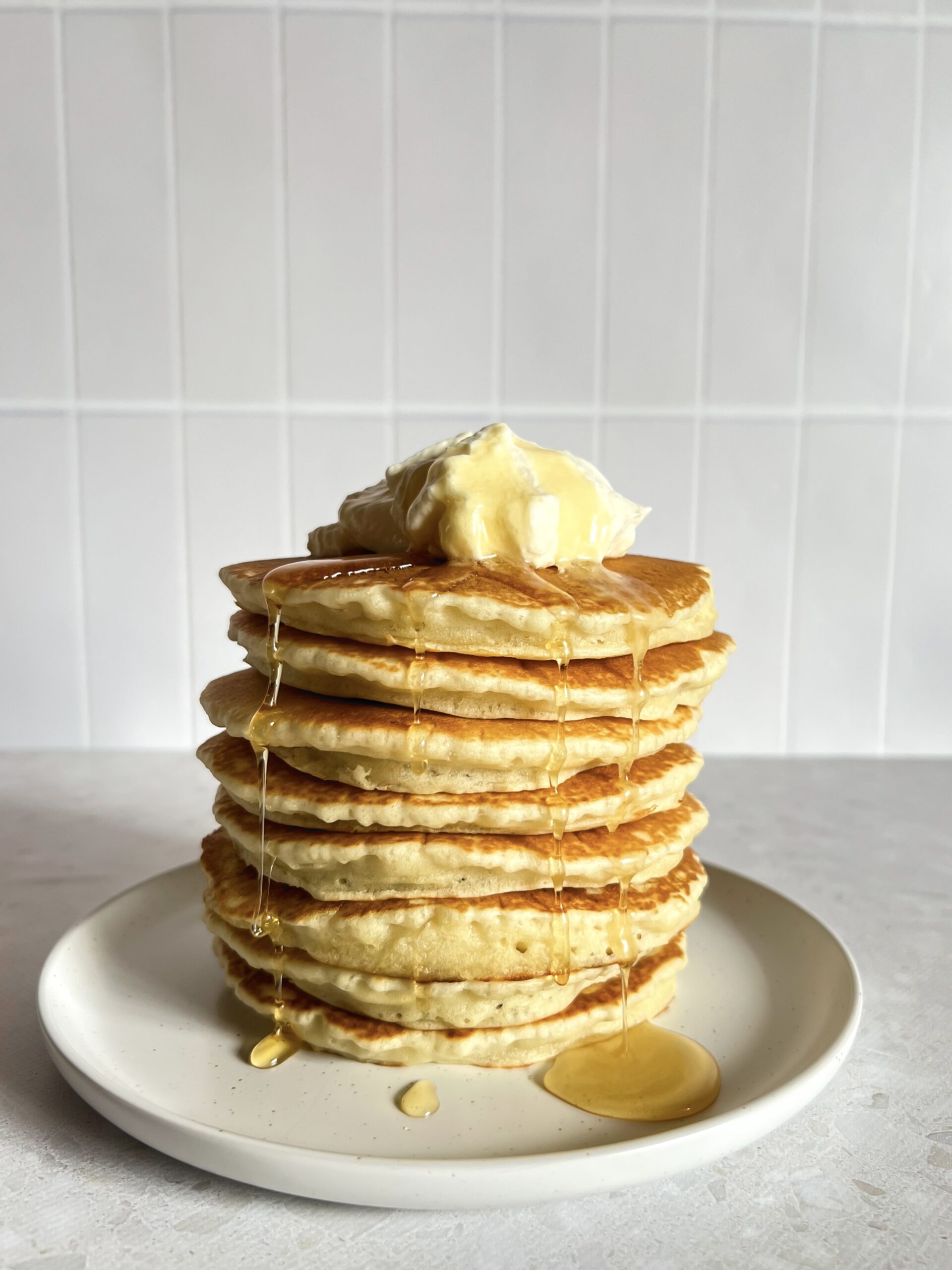 Stack of classic pancakes with a dollop of cream and honey drizzle