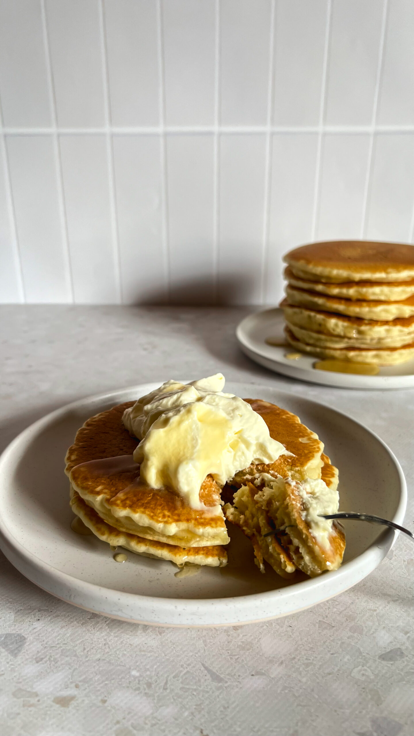 Plated classic fluffy pancakes with a dollop of cream and honey drizzle